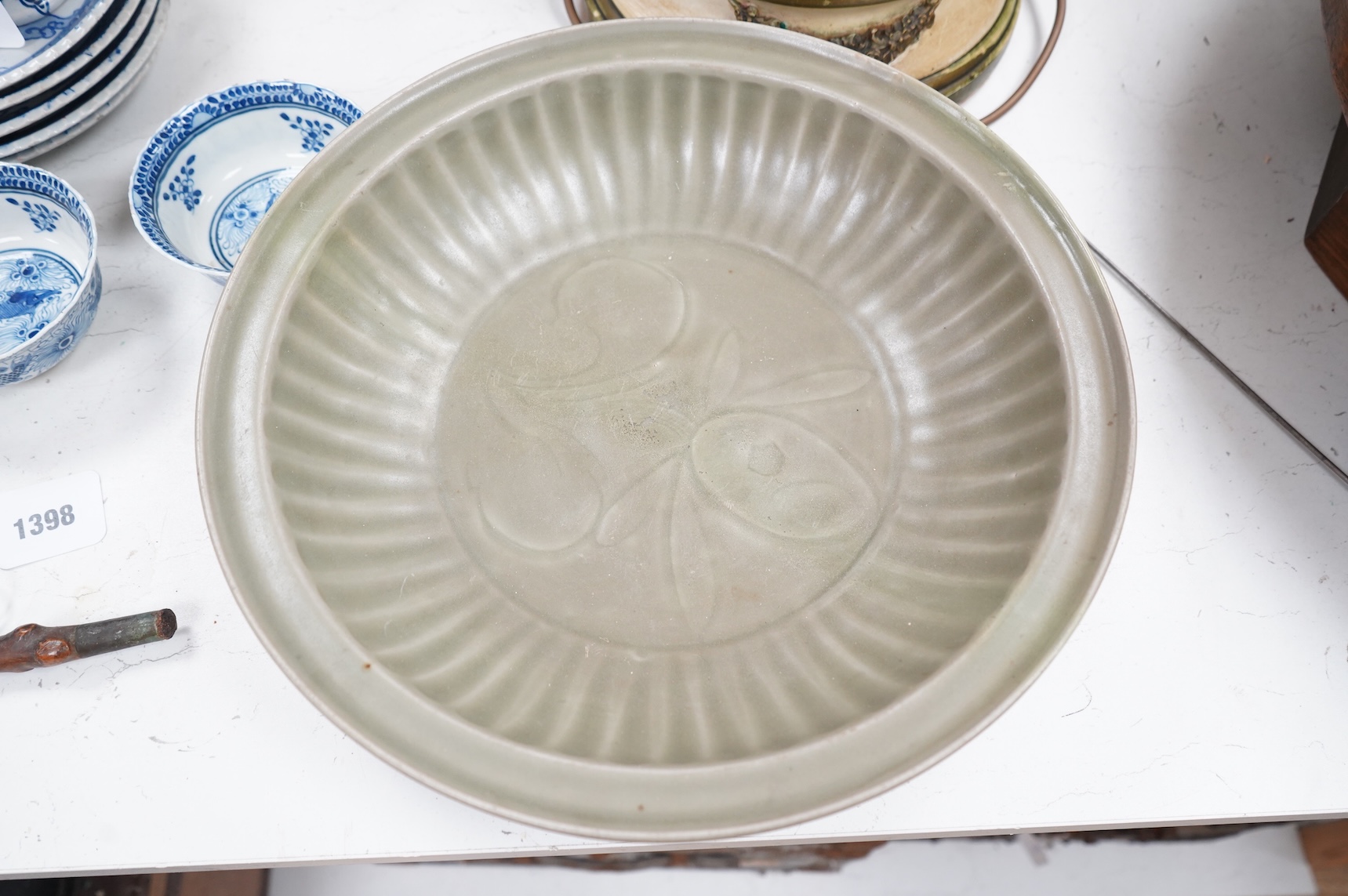 A 17th century Chinese celadon dish decorated in low relief, restored, 36cm in diameter